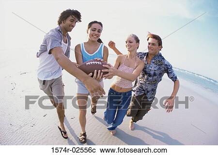 Two teenage couples playing football on the beach View Large Photo Image Stock Image - Two teenage couples playing football on the beach. Fotosearch