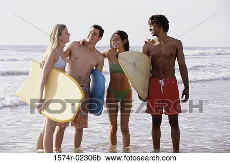 Two teenage couples standing on the beach holding boogie boards View Large Photo Image Stock Image - Two teenage couples standing on the beach holding boogie boards. Fotosearch