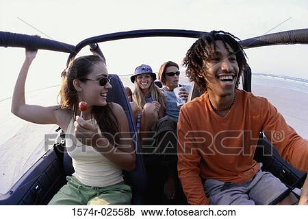 Stock Image - Two young couples sitting in a jeep. Fotosearch