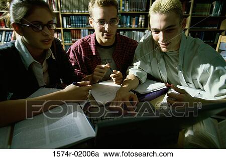 Stock Image - Two young men and a young woman using a laptop. Fotosearch