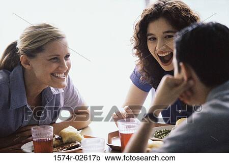 Two young women and a young man sitting in a restaurant View Large Photo Image Stock Image - Two young women and a young man sitting in a restaurant. Fotosearch
