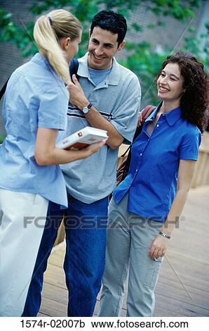 Two young women and a young man talking View Large Photo Image Stock Image - Two young women and a young man talking. Fotosearch