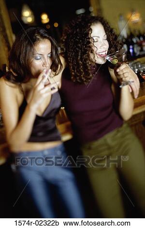 Two young women drinking in a bar View Large Photo Image Stock Image - Two young women drinking in a bar. Fotosearch