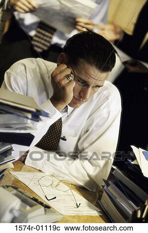 Stock Image - Young businessman sitting at his desk at work. Fotosearch