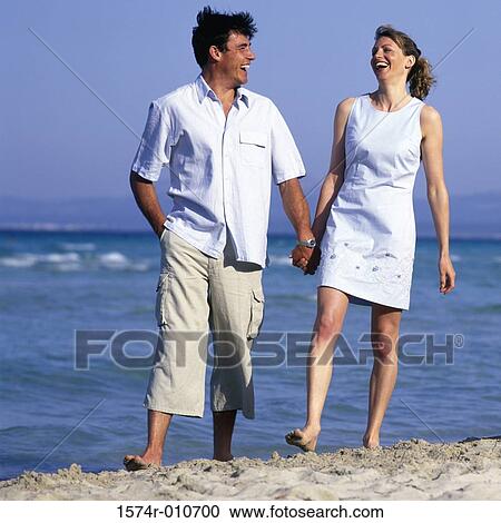 Young couple holding hands walking on the beach View Large Photo Image Stock Image - Young couple holding hands walking on the beach. Fotosearch