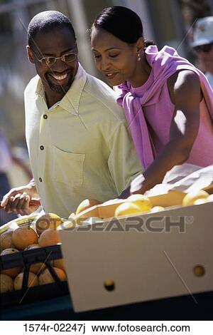 Young couple picking oranges from a shop in a market View Large Photo Image Stock Image - Young couple picking oranges from a shop in a market. Fotosearch