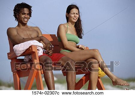 Young couple sitting on a lifeguard chair on the beach View Large Photo Image Stock Image - Young couple sitting on a lifeguard chair on the beach. Fotosearch