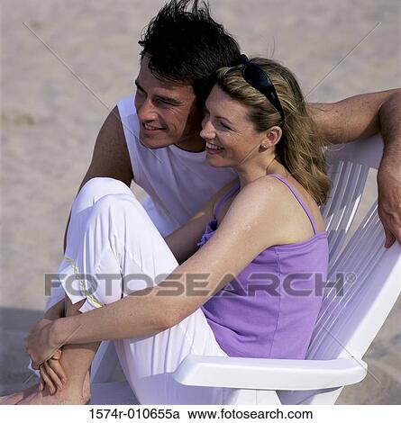 Stock Image - Young couple sitting together at the beach. Fotosearch