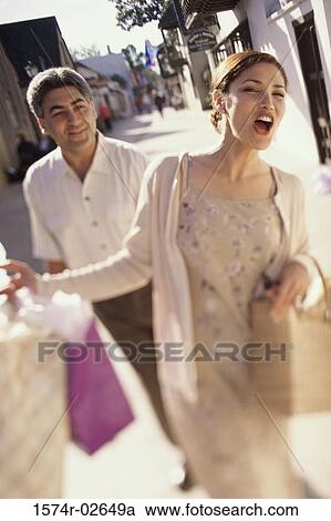 Stock Image - Young couple walking with shopping bags. Fotosearch