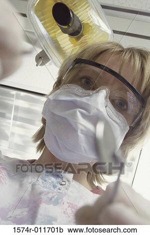 Stock Image - Young female dentist wearing protective gear. Fotosearch