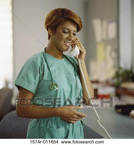 Picture - Young female doctor talking on a telephone. Fotosearch