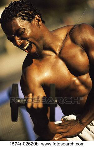 Stock Image - Young man exercising with a dumbbell. Fotosearch