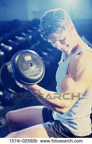 Young man exercising with dumbbells View Large Photo Image Stock Image - Young man exercising with dumbbells. Fotosearch