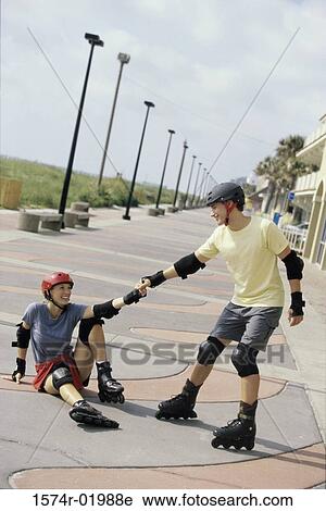 Young man helping up a young woman on inline skates View Large Photo Image Stock Image - Young man helping up a young woman on inline skates. Fotosearch