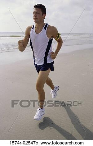 Stock Image - Young man jogging on the beach. Fotosearch