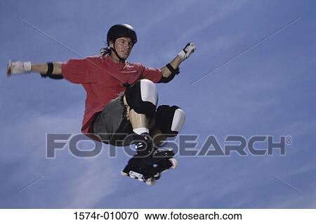 Stock Image - Young man jumping in mid air wearing inline skates. Fotosearch