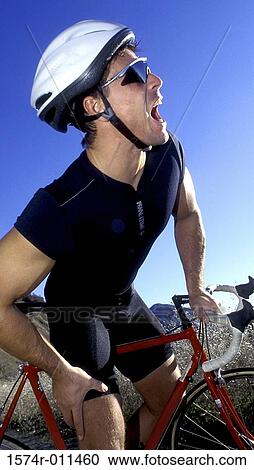 Stock Image - Young man on a bicycle grabbing his leg in pain. Fotosearch