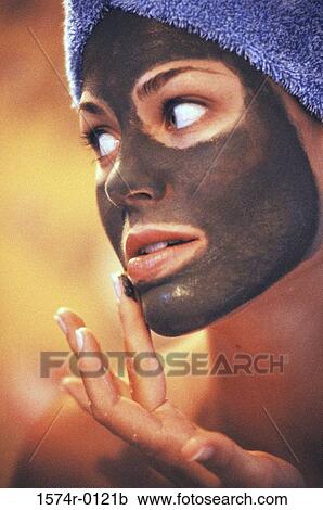 Stock Image - Young woman applying a facial mask. Fotosearch