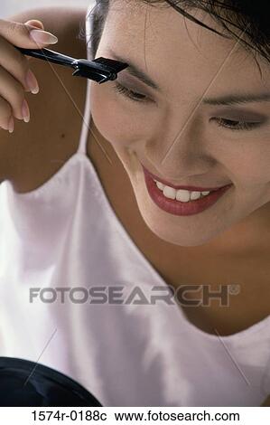 Young woman applying make-up in a mirror View Large Photo Image Stock Image - Young woman applying make-up in a mirror. Fotosearch