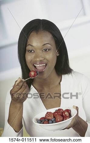Stock Image - Young woman eating a strawberry. Fotosearch