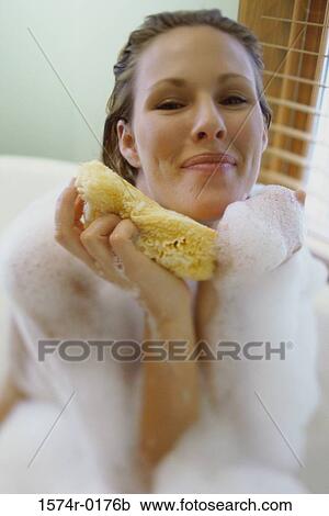 Young woman holding a sponge in a bubble bath View Large Photo Image Stock Image - Young woman holding a sponge in a bubble bath. Fotosearch