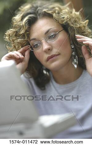 Stock Image - Young woman looking at a laptop. Fotosearch