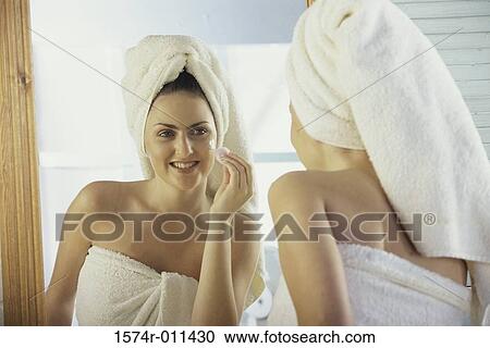 Young woman looking into a mirror cleaning her face View Large Photo Image Stock Image - Young woman looking into a mirror cleaning her face. Fotosearch