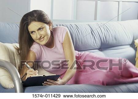 Young woman lying on a couch View Large Photo Image Stock Photo - Young woman lying on a couch. Fotosearch