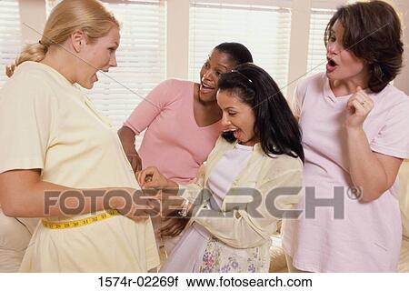 Stock Image - Young woman measuring a pregnant woman's abdomen. Fotosearch