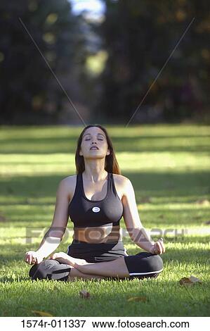 Stock Photo - Young woman meditating on a lawn. Fotosearch