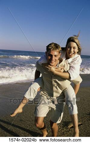 Young woman riding piggyback on a young man at the beach View Large Photo Image Stock Image - Young woman riding piggyback on a young man at the beach. Fotosearch