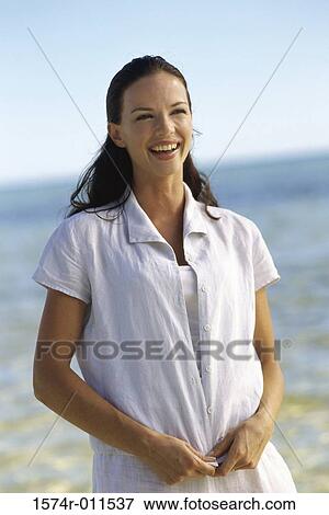 Young woman standing on the beach smiling View Large Photo Image Stock Photo - Young woman standing on the beach smiling. Fotosearch