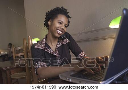 Young woman talking on a mobile phone using a laptop View Large Photo Image Stock Image - Young woman talking on a mobile phone using a laptop. Fotosearch