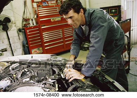 Auto mechanic working over the engine bay of a car View Large Photo Image Stock Image - Auto mechanic working over the engine bay of a car. Fotosearch