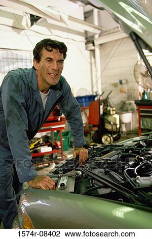 Auto mechanic working over the engine bay of a car View Large Photo Image Stock Image - Auto mechanic working over the engine bay of a car. Fotosearch