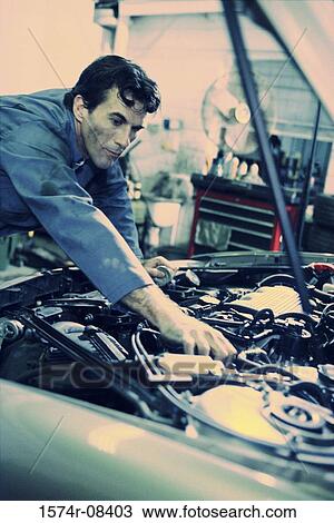 Auto mechanic working over the engine bay of a car View Large Photo Image Stock Image - Auto mechanic working over the engine bay of a car. Fotosearch