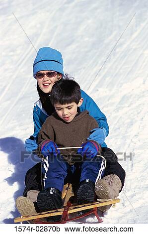 Stock Image - Boy and a girl riding a sled. Fotosearch