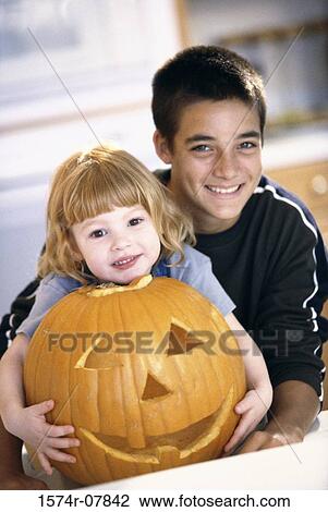 Stock Image - Boy and a girl smiling next to a jack-o-lantern. Fotosearch