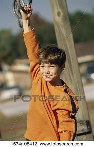 Stock Image - Boy hanging from a jungle gym. Fotosearch