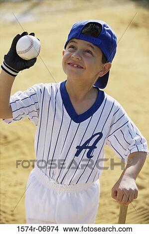 Picture - Boy in a baseball uniform holding a ball. Fotosearch