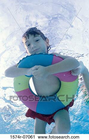 Stock Image - Boy swimming underwater holding inflatable ring. Fotosearch