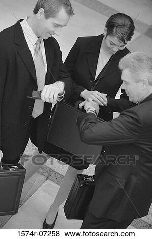 Business executives looking at their wristwatches View Large Photo Image Stock Photo - Business executives looking at their wristwatches. Fotosearch