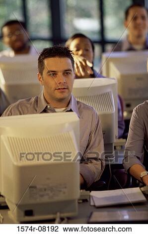 Business executives sitting in front of computer monitors in an office View Large Photo Image Stock Image - Business executives sitting in front of computer monitors in an office. Fotosearch