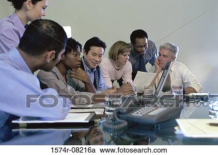 Stock Image - Business executives sitting together in a conference room. Fotosearch