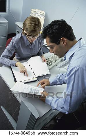 Stock Image - Businessman and a businesswoman reading documents. Fotosearch