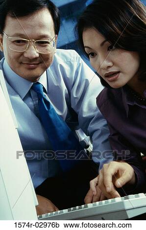 Businessman and a businesswoman sitting in front of a computer View Large Photo Image Stock Image - Businessman and a businesswoman sitting in front of a computer. Fotosearch