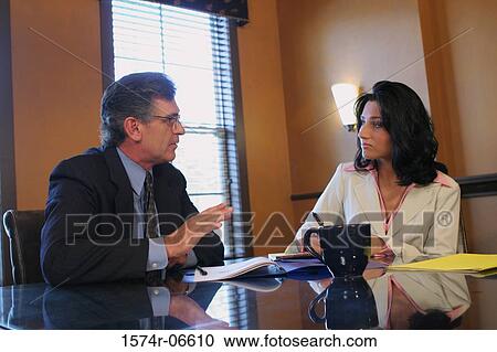 Stock Image - Businessman and a businesswoman sitting in an office. Fotosearch