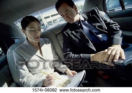 Businessman and a businesswoman sitting at the back seat of a car View Large Photo Image Stock Image - Businessman and a businesswoman sitting at the back seat of a car. Fotosearch