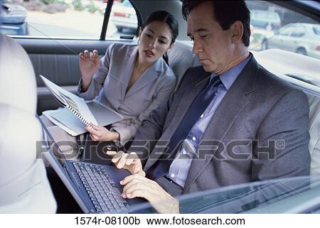 Businessman and a businesswoman sitting in the back seat of a car View Large Photo Image Stock Image - Businessman and a businesswoman sitting in the back seat of a car. Fotosearch