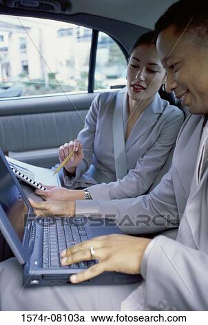 Businessman and a businesswoman sitting in the back seat of a car View Large Photo Image Stock Image - Businessman and a businesswoman sitting in the back seat of a car. Fotosearch